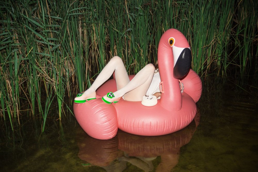 Woman on inflatable flamingos naked