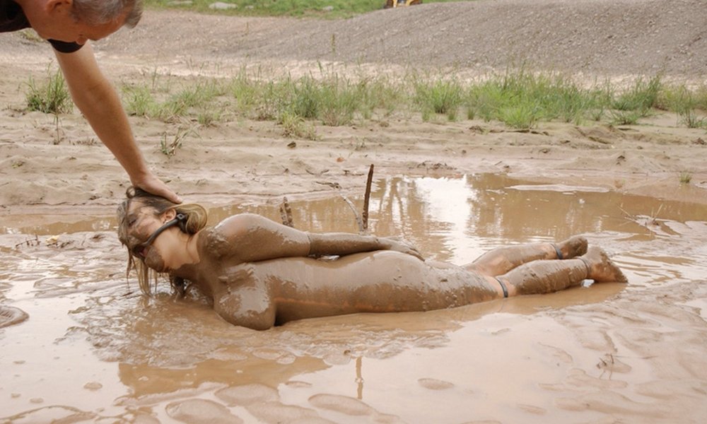 The girl is lying in the mud nude