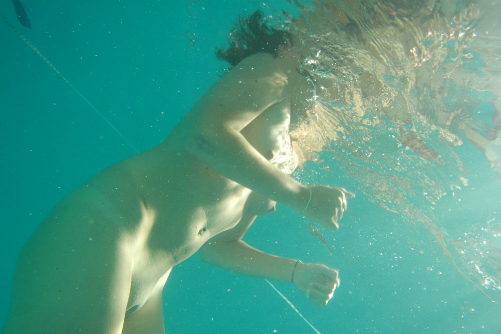 The girl bathes naked under water in