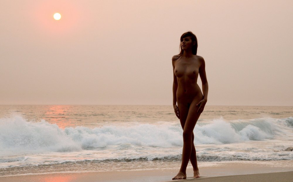 Naked woman on sunset background