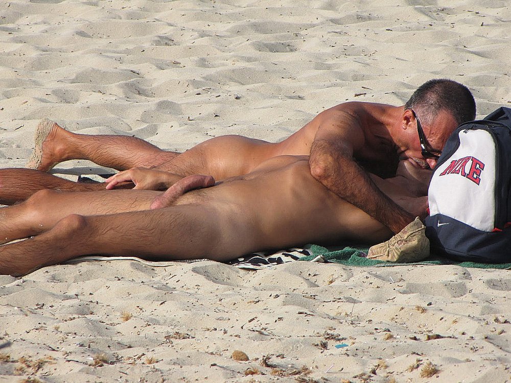 A naked man lies on the beach
