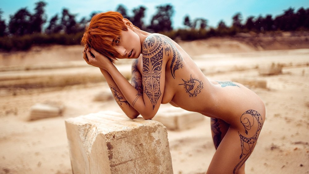Naked women on the beach with tattoo and piercing