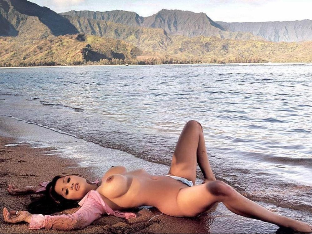 A naked woman lies on the seashore